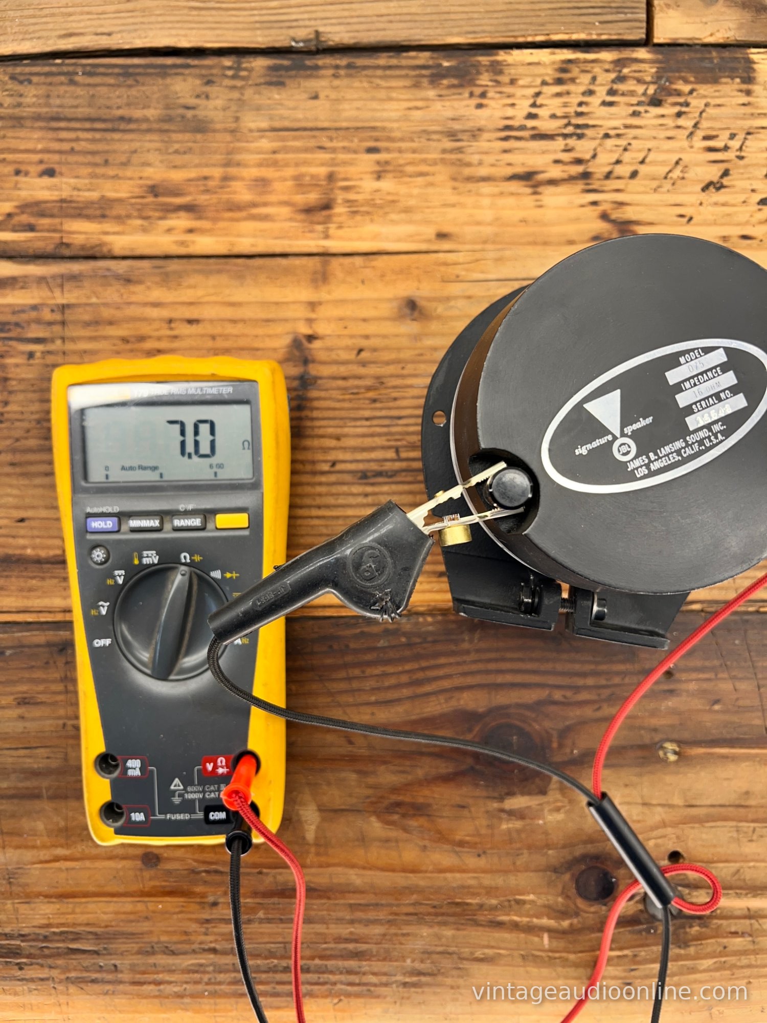 Multimeter connected by clip leads to a vintage JBL tweeter